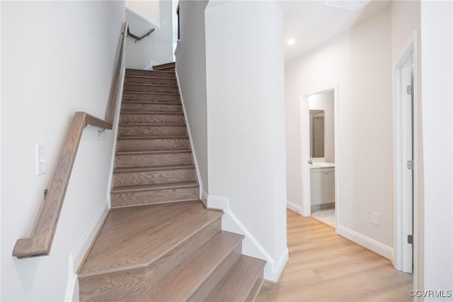 stairway featuring wood finished floors, baseboards, and recessed lighting