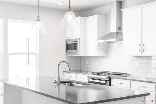kitchen featuring backsplash, white cabinets, wall chimney exhaust hood, stainless steel appliances, and a sink