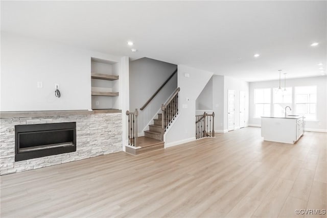 unfurnished living room featuring a sink, light wood finished floors, and recessed lighting