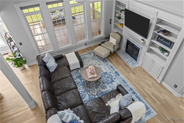 living room featuring a fireplace, light wood finished floors, and baseboards
