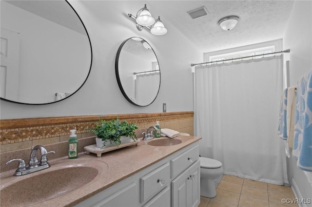 bathroom featuring toilet, tile walls, a sink, and visible vents