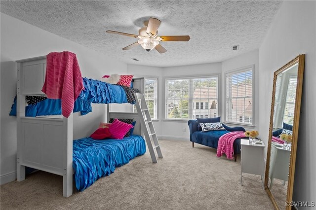 carpeted bedroom featuring a textured ceiling, visible vents, a ceiling fan, and baseboards