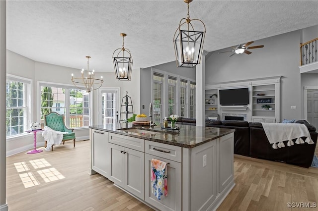kitchen with light wood-style floors, ceiling fan with notable chandelier, open floor plan, and a sink