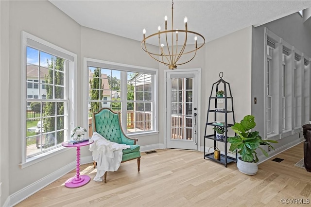 sitting room with baseboards, wood finished floors, a notable chandelier, and plenty of natural light
