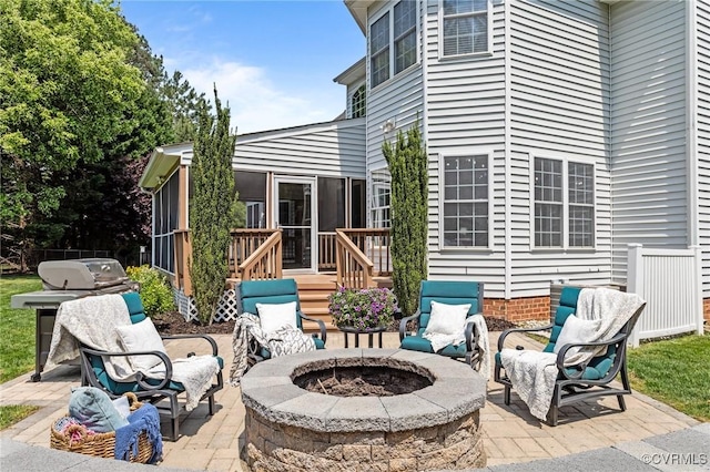 view of patio / terrace with an outdoor fire pit and a sunroom