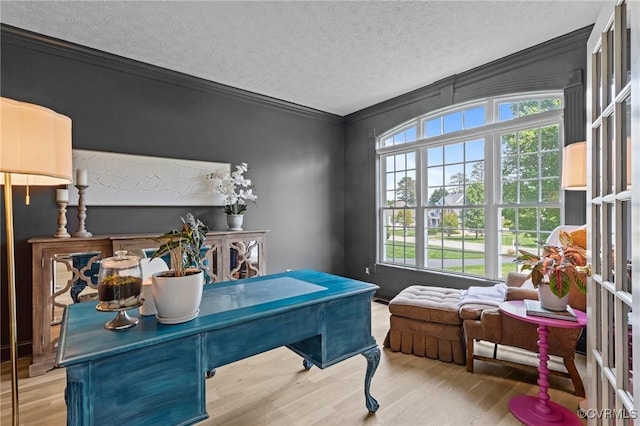 home office featuring a textured ceiling, wood finished floors, a wealth of natural light, and ornamental molding