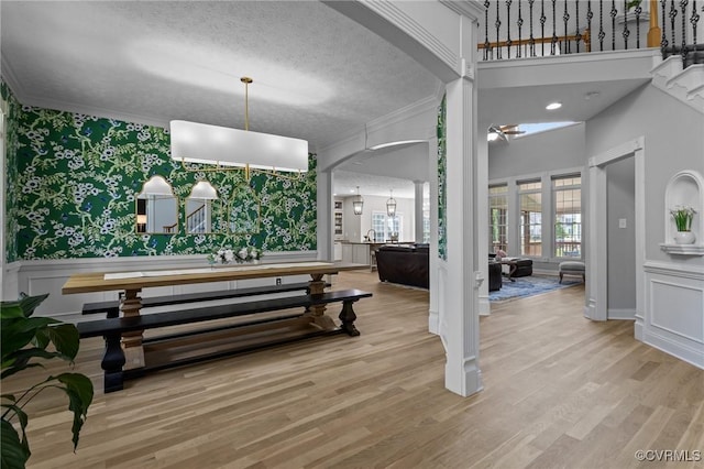 interior space featuring wallpapered walls, ornamental molding, wood finished floors, and arched walkways