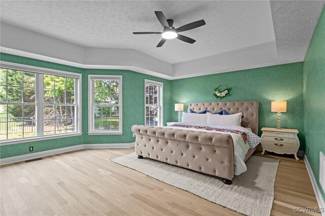 bedroom featuring wood finished floors, baseboards, visible vents, a ceiling fan, and a textured ceiling