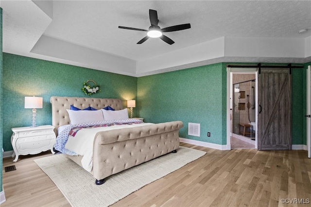 bedroom with wood finished floors, visible vents, and baseboards