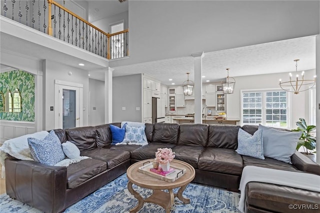 living area featuring a towering ceiling, recessed lighting, a chandelier, and plenty of natural light