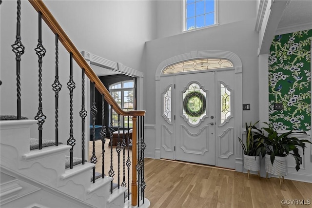 entrance foyer featuring stairway, plenty of natural light, light wood-style flooring, and a high ceiling