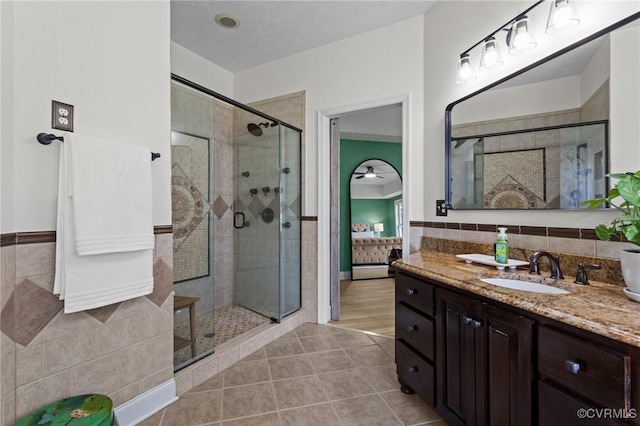 ensuite bathroom featuring vanity, ceiling fan, tile patterned floors, a stall shower, and ensuite bathroom