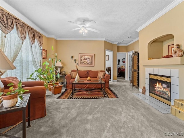 living room featuring carpet flooring, a ceiling fan, a fireplace, a textured ceiling, and ornamental molding