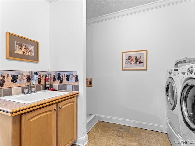 washroom with ornamental molding, a textured ceiling, washing machine and clothes dryer, a sink, and cabinet space