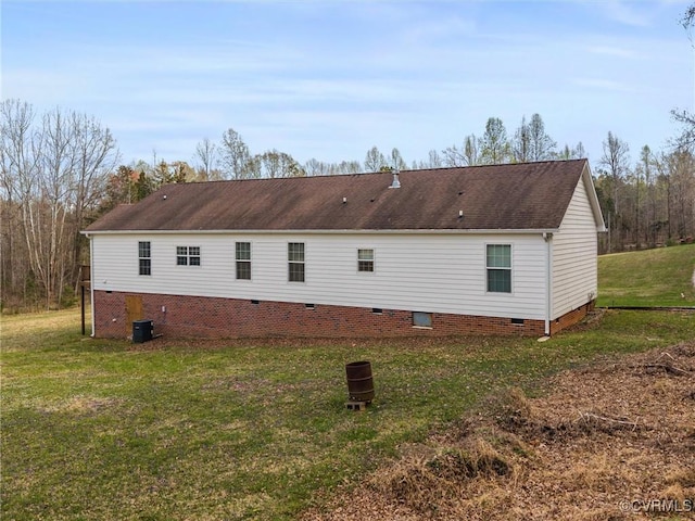 rear view of house with a shingled roof, crawl space, central AC, and a lawn