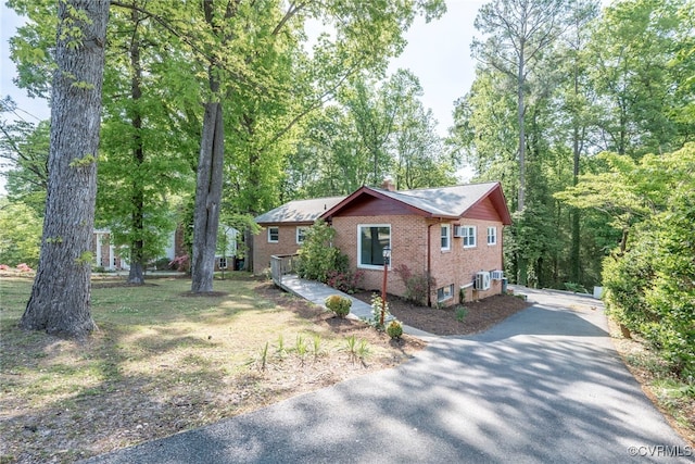 view of property exterior featuring a chimney, driveway, and brick siding