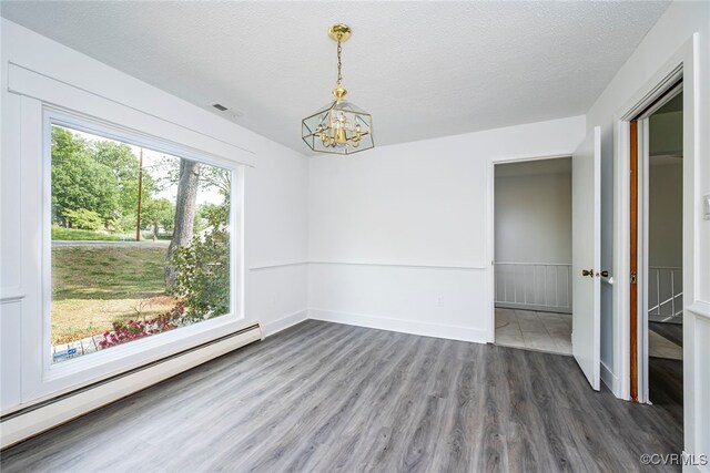 unfurnished room featuring a textured ceiling, wood finished floors, baseboards, a baseboard radiator, and an inviting chandelier