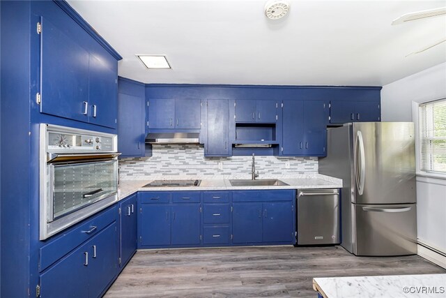 kitchen with open shelves, appliances with stainless steel finishes, a sink, decorative backsplash, and wood finished floors