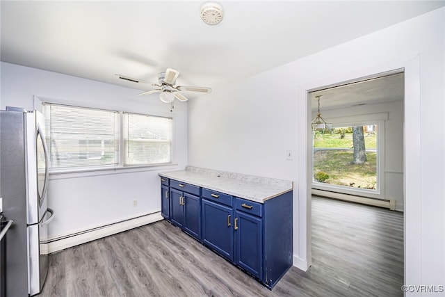 kitchen with baseboard heating, blue cabinetry, light wood-style flooring, freestanding refrigerator, and a baseboard radiator