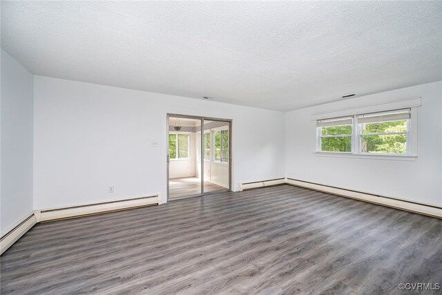 empty room with a textured ceiling, baseboards, a baseboard heating unit, and wood finished floors