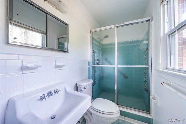 bathroom featuring a sink, tile walls, toilet, and a shower stall