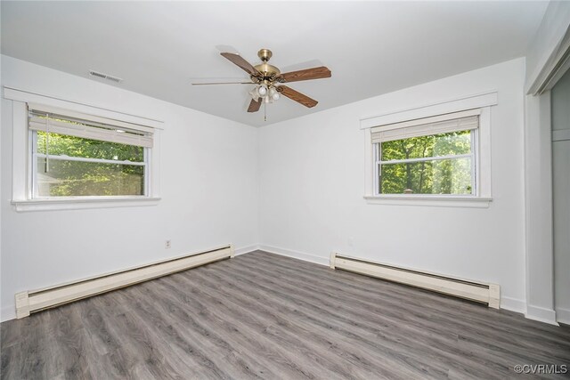 spare room with visible vents, a ceiling fan, wood finished floors, a baseboard heating unit, and a baseboard radiator