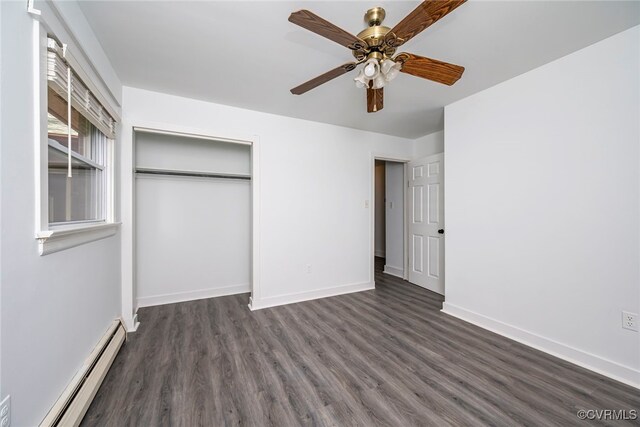 unfurnished bedroom featuring a closet, baseboards, a baseboard heating unit, and dark wood-style floors