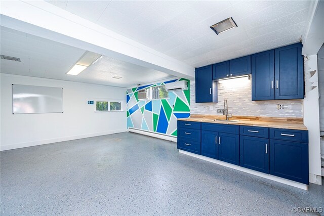 garage featuring visible vents, baseboards, baseboard heating, a wall unit AC, and a sink