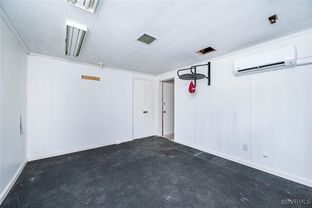 garage with visible vents, a wall mounted air conditioner, and baseboards