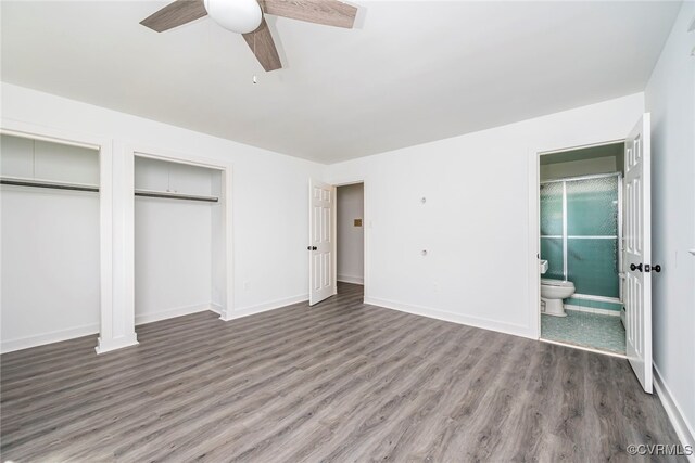unfurnished bedroom with multiple closets, baseboards, ensuite bath, and wood finished floors