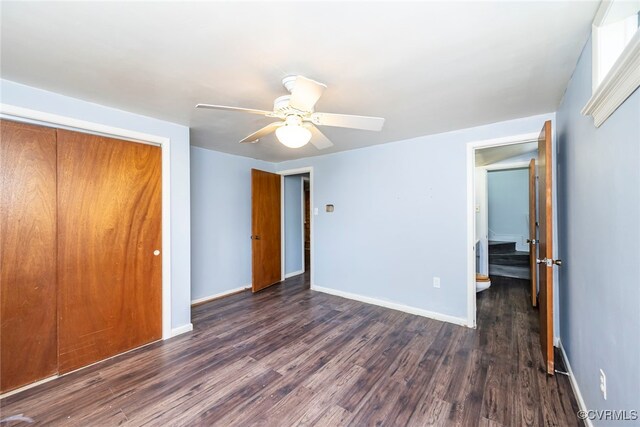 unfurnished bedroom featuring dark wood-style flooring, baseboards, a ceiling fan, and a closet