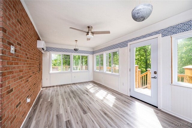 unfurnished sunroom with a deck, a wall mounted air conditioner, brick wall, and wood finished floors