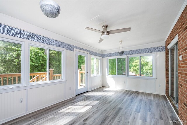 unfurnished sunroom with crown molding, wood finished floors, brick wall, and a deck