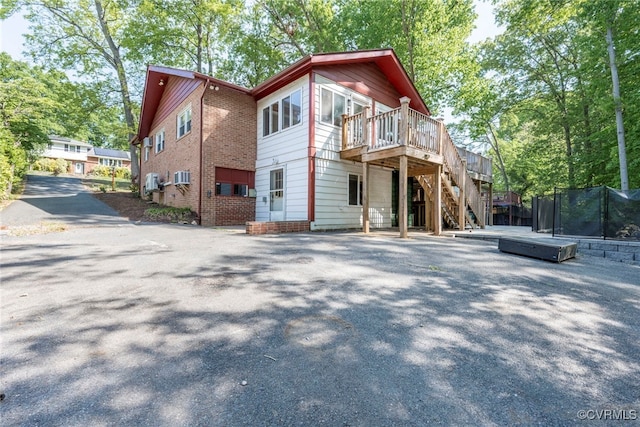 rear view of property featuring stairs, an AC wall unit, a trampoline, and a deck