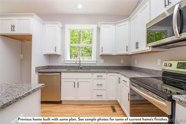 59 Jamestown Ln, Bracey, VA 23919 - kitchen featuring white cabinets, stainless steel appliances, light wood-style flooring, and a sink