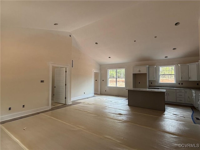 162 Tradewind Xing, Bracey, VA 23919 - kitchen with a center island, plenty of natural light, baseboards, white cabinetry, and high vaulted ceiling