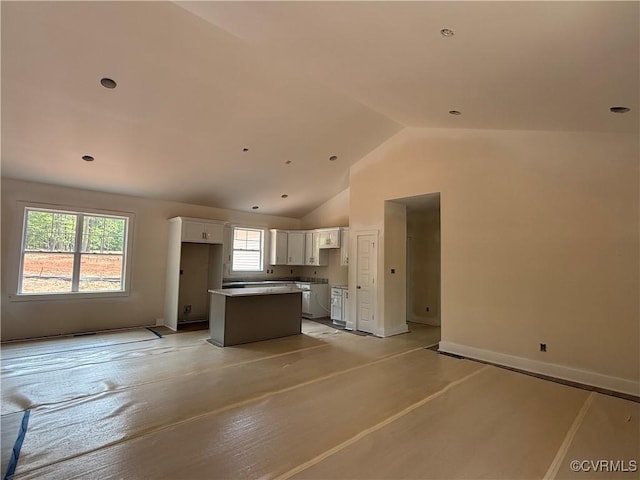 162 Tradewind Xing, Bracey, VA 23919 - kitchen featuring white cabinetry, vaulted ceiling, a center island, baseboards, and open floor plan