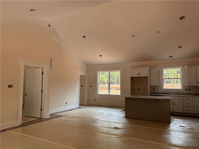 162 Tradewind Xing, Bracey, VA 23919 - kitchen featuring white cabinets, a kitchen island, baseboards, high vaulted ceiling, and light wood-type flooring