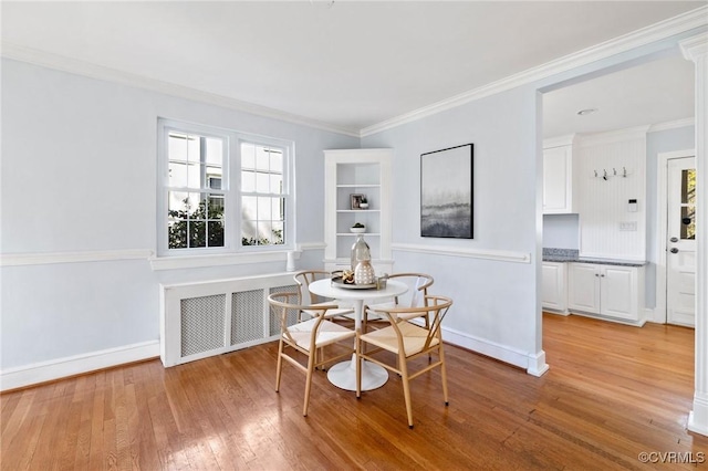 dining room with crown molding, radiator, baseboards, and light wood-style floors