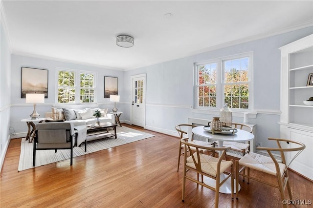 dining area with wood finished floors, baseboards, and ornamental molding