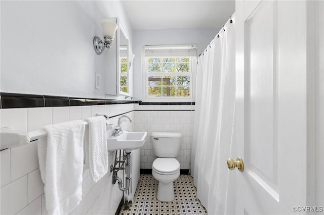full bathroom with wainscoting, tile walls, a sink, and toilet