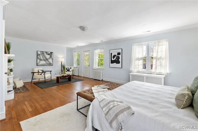 bedroom with wood finished floors, radiator heating unit, and multiple windows