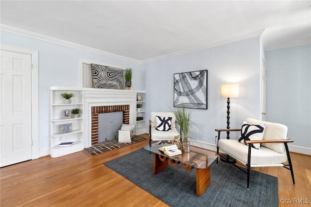 sitting room featuring a fireplace, baseboards, crown molding, and wood finished floors