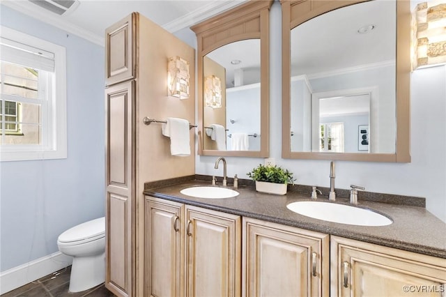bathroom featuring toilet, crown molding, a sink, and visible vents