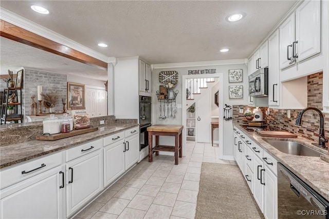 kitchen with a sink, stainless steel microwave, tasteful backsplash, white cabinetry, and dishwashing machine