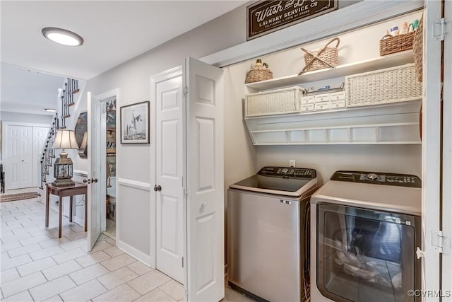 clothes washing area with washing machine and clothes dryer, tile patterned floors, and laundry area