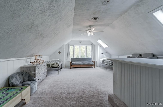 carpeted bedroom with a ceiling fan, visible vents, and lofted ceiling with skylight