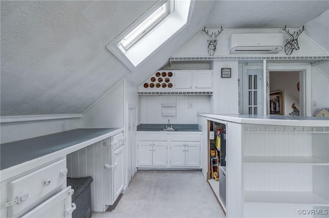 kitchen with white cabinets, open shelves, lofted ceiling with skylight, and a wall mounted AC