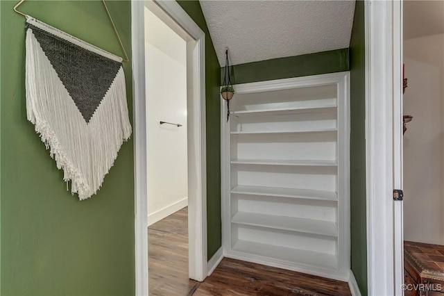 staircase with baseboards, wood finished floors, and a textured ceiling