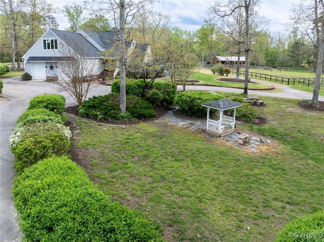 view of yard with fence and aphalt driveway